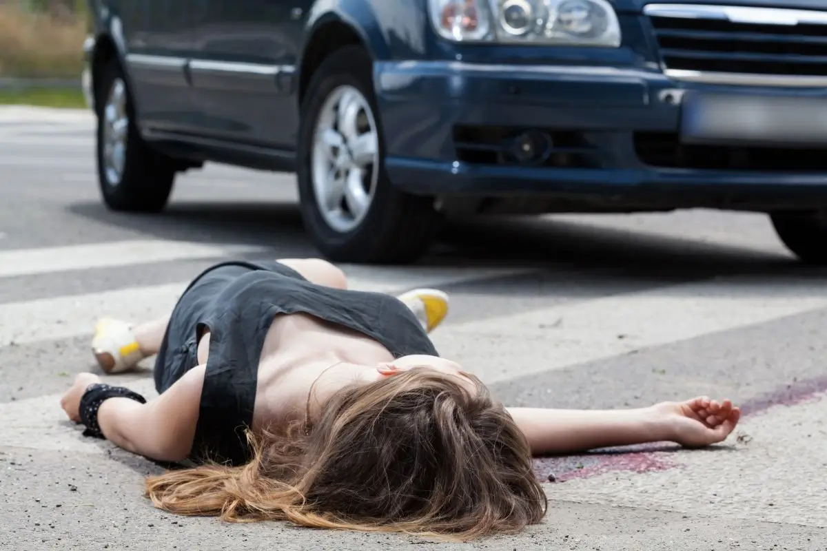 Accident scene with a person lying injured on the road near a vehicle, illustrating the aftermath of a car collision.