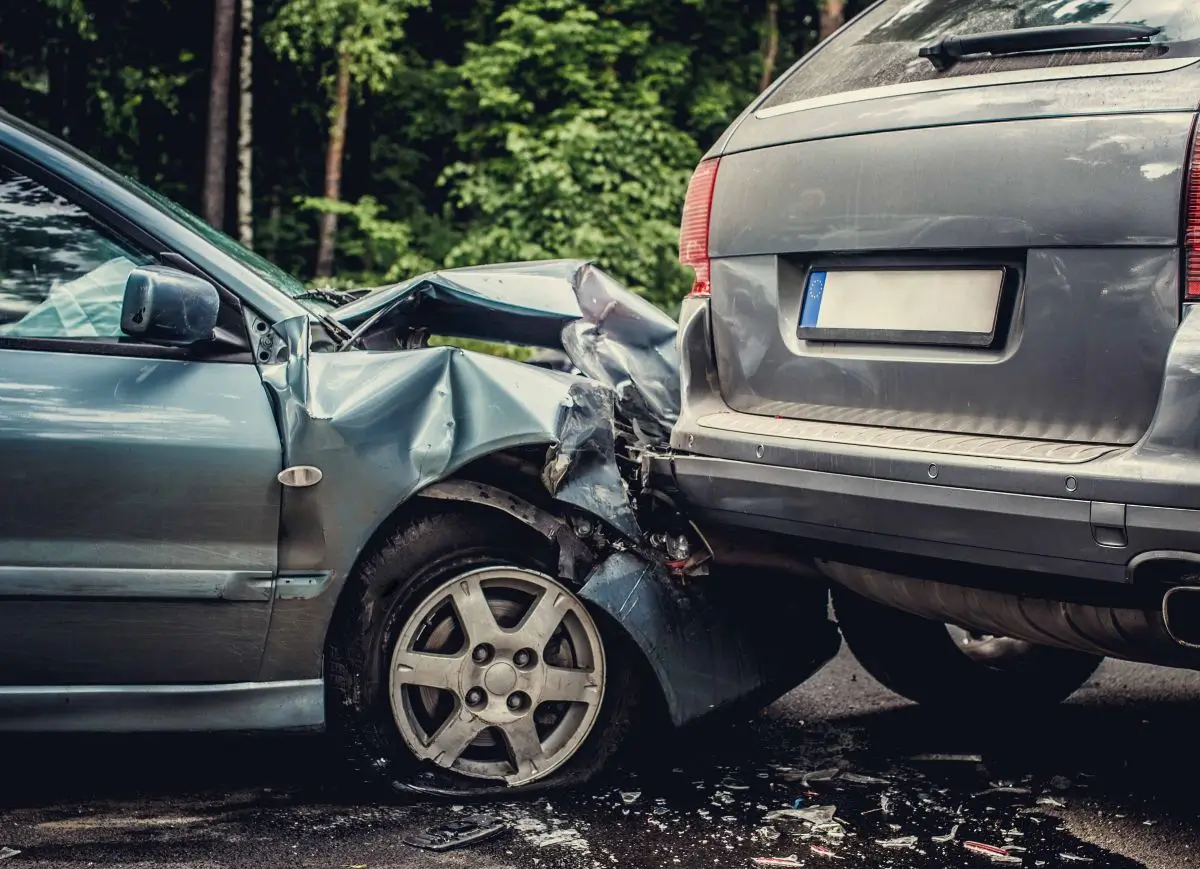 Two damaged cars after a rear-end collision on the road, showing severe front-end and back-end impact.