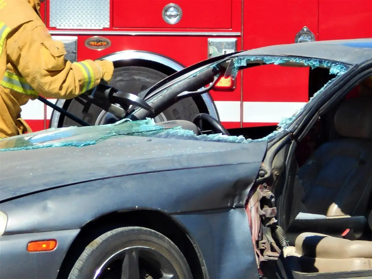 Firefighter using rescue equipment to cut open a damaged car after a serious accident.