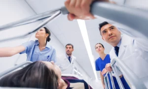 Medical team hurriedly wheeling a patient on a gurney through a hospital corridor — doctors and nurses focused and determined, capturing urgency, critical care, and potential emergency-room negligence or malpractice.