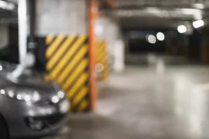 Dimly lit parking garage with a parked vehicle, illustrating conditions that may contribute to slip and fall accidents or other injuries in Massachusetts parking garages.
